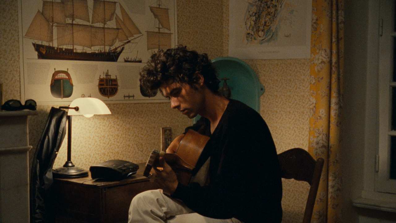 a man in his room playing guitar